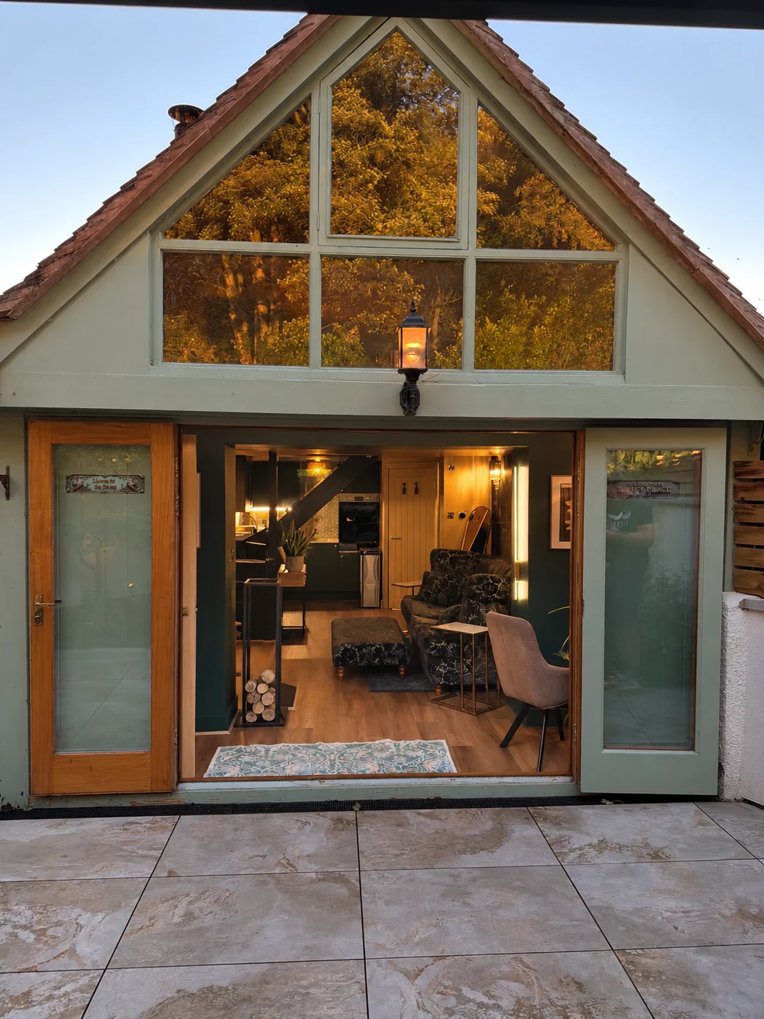 Warmly lit exterior of Nordic Garden Spa Retreat, with doors opening into the living area