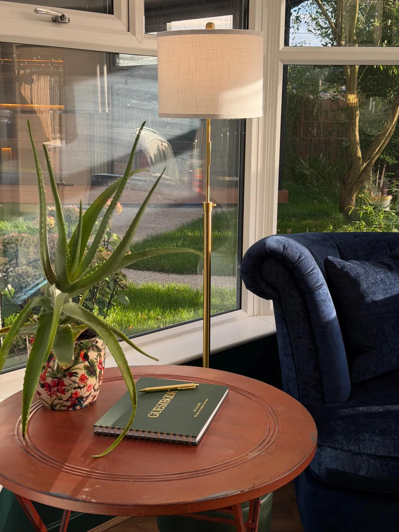 Sunny conservatory corner with guest book and velvet sofa