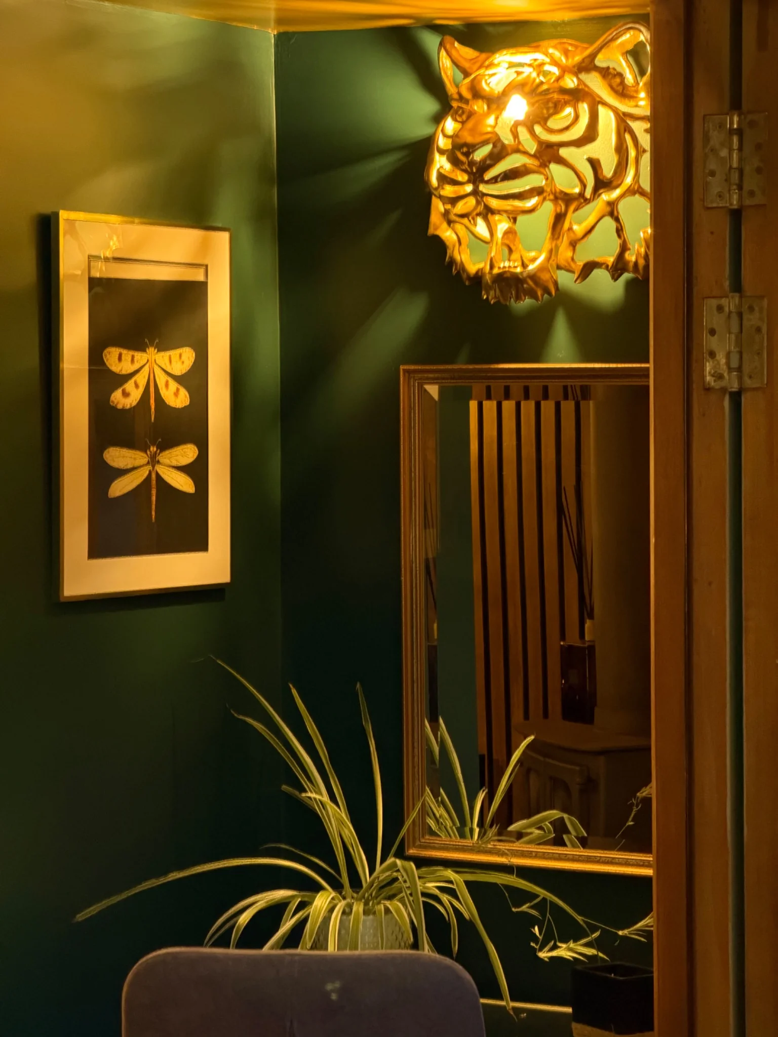 Atmospheric dark green interior with gold tiger wall light and botanical details